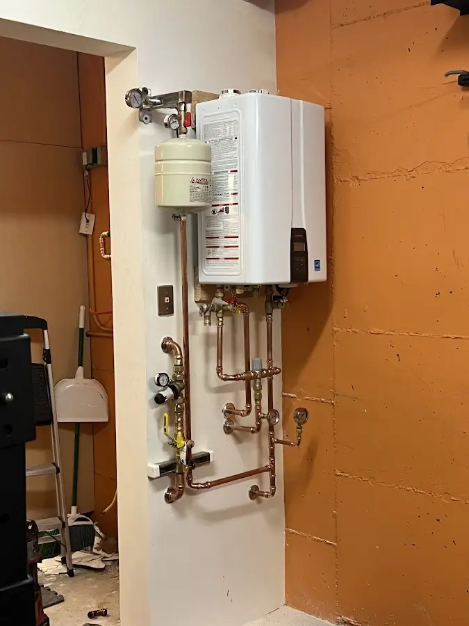 Plumbing technician inspecting water heater connections in Addison